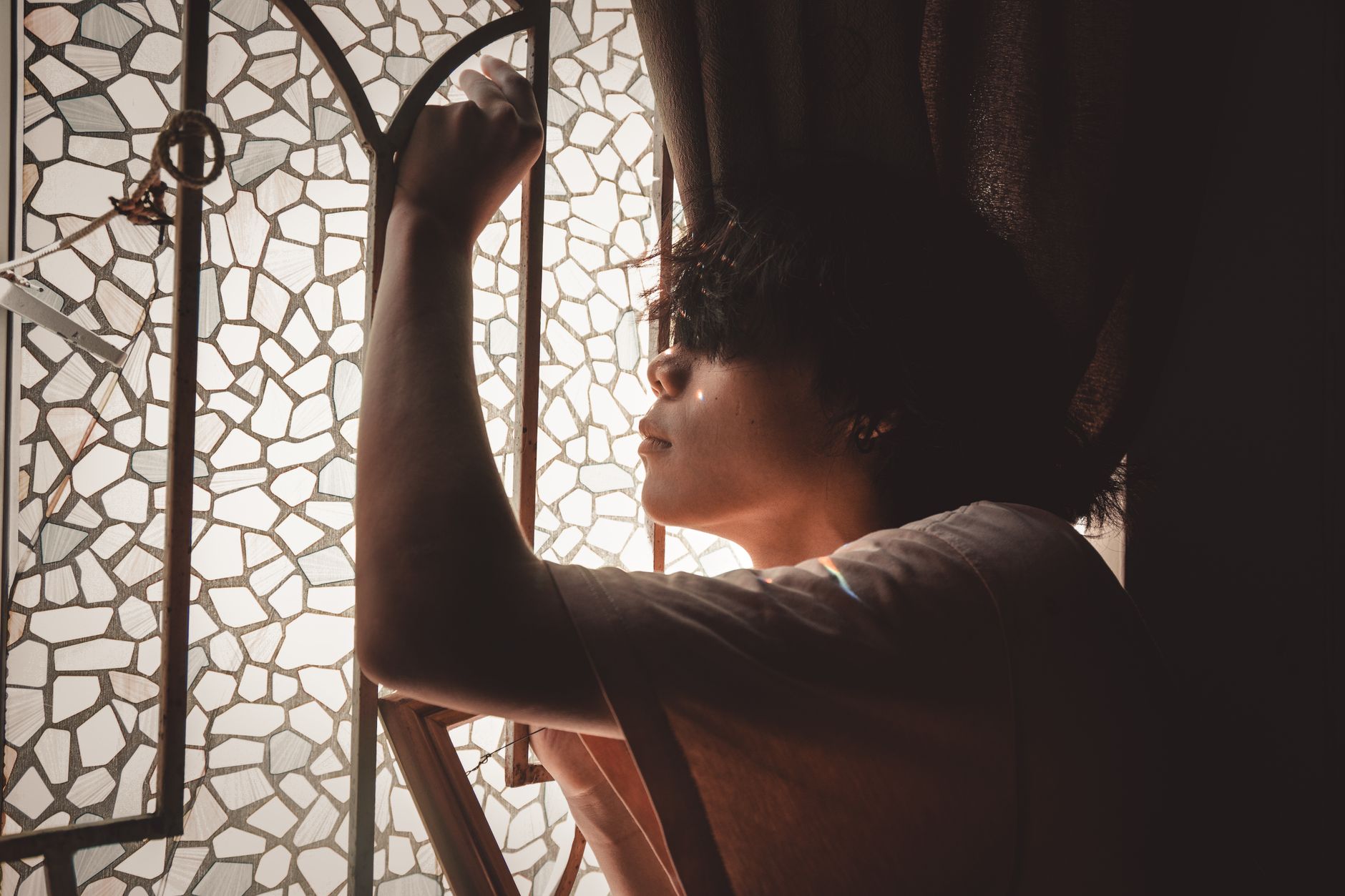 A person opening a window into warm morning light