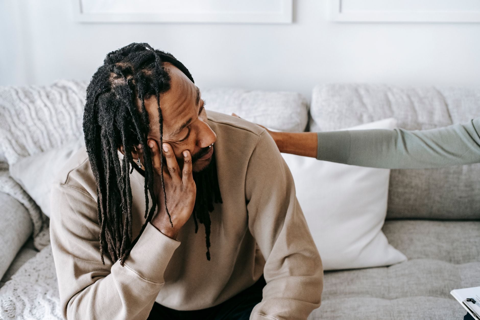 A man sitting on a couch with his head in his hand