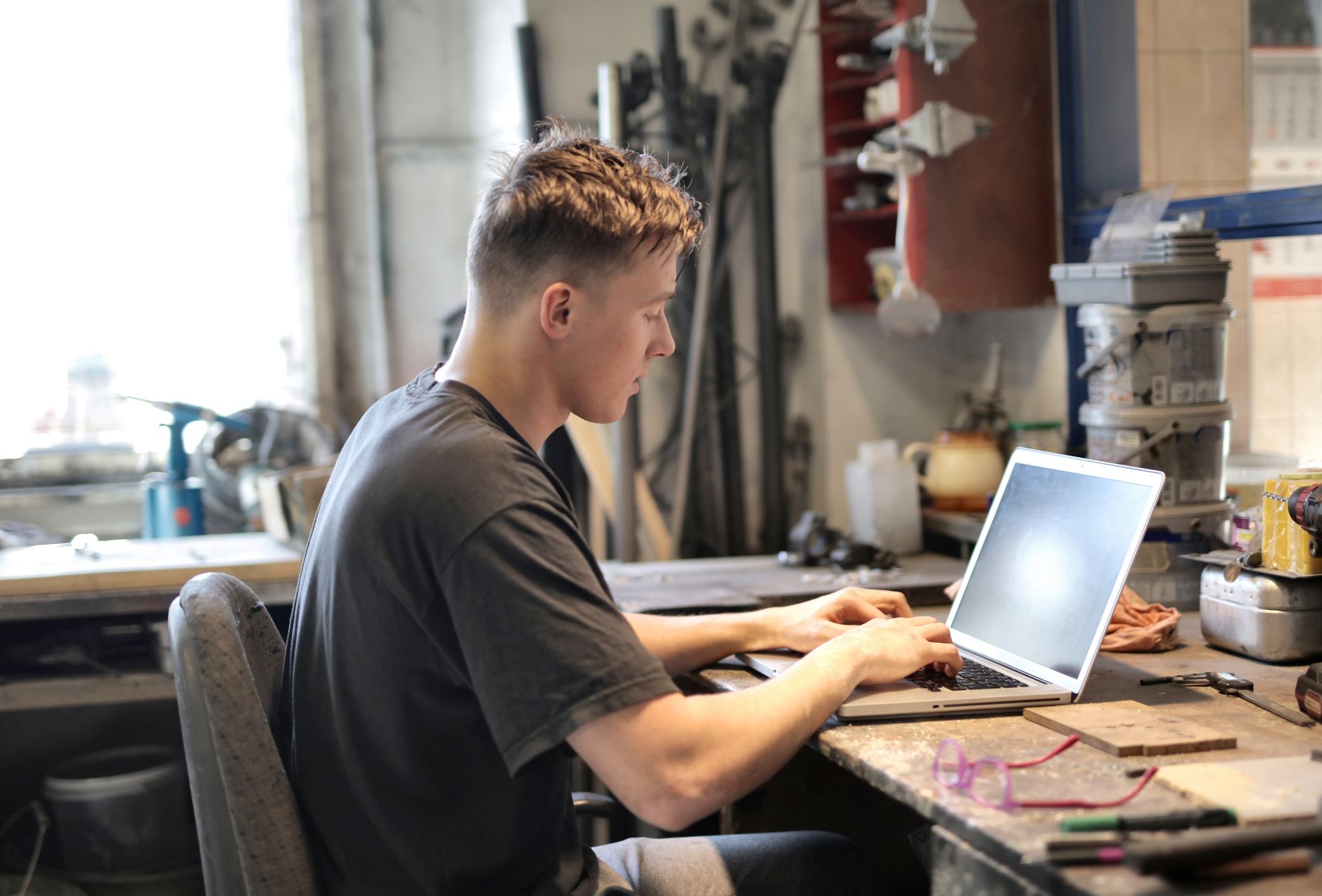 A man working at a laptop on a workbench
