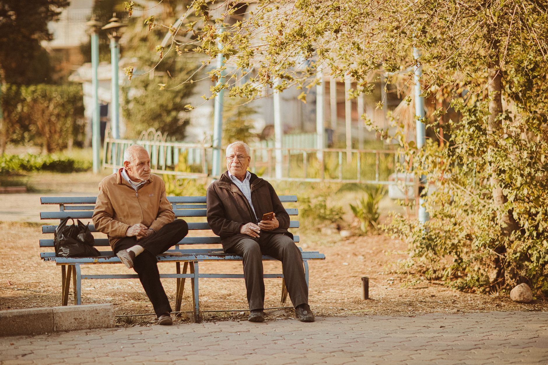 Two men sitting on a park bench in autumn