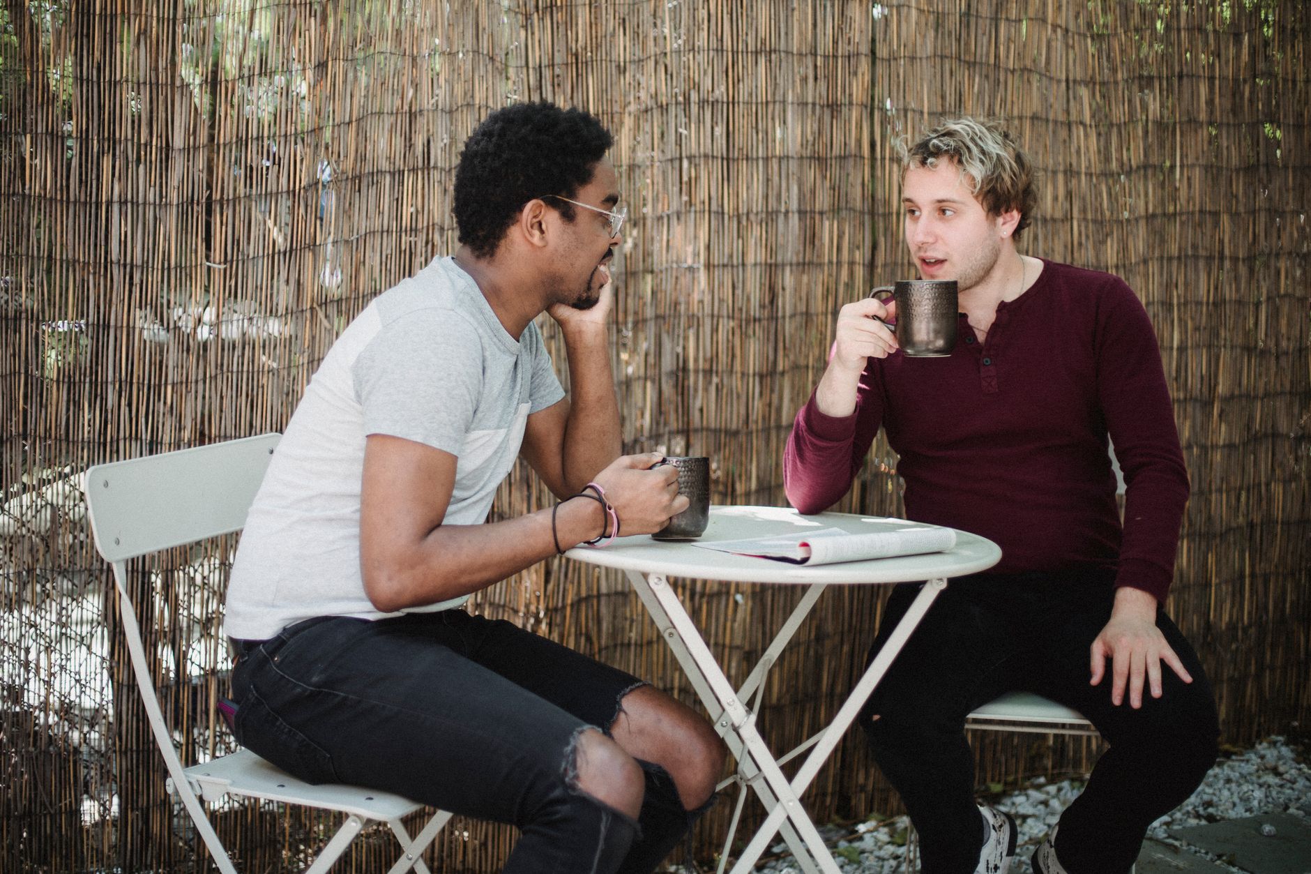 Two men talking across a small cafe table