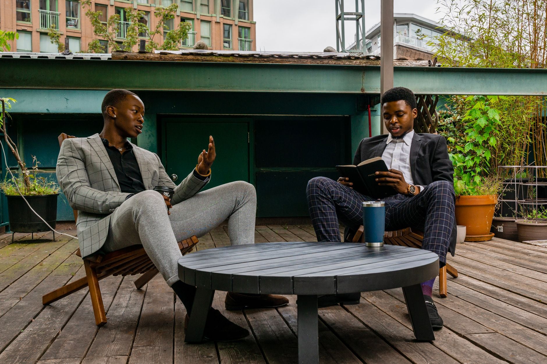 Two men seated outdoors on a deck, talking