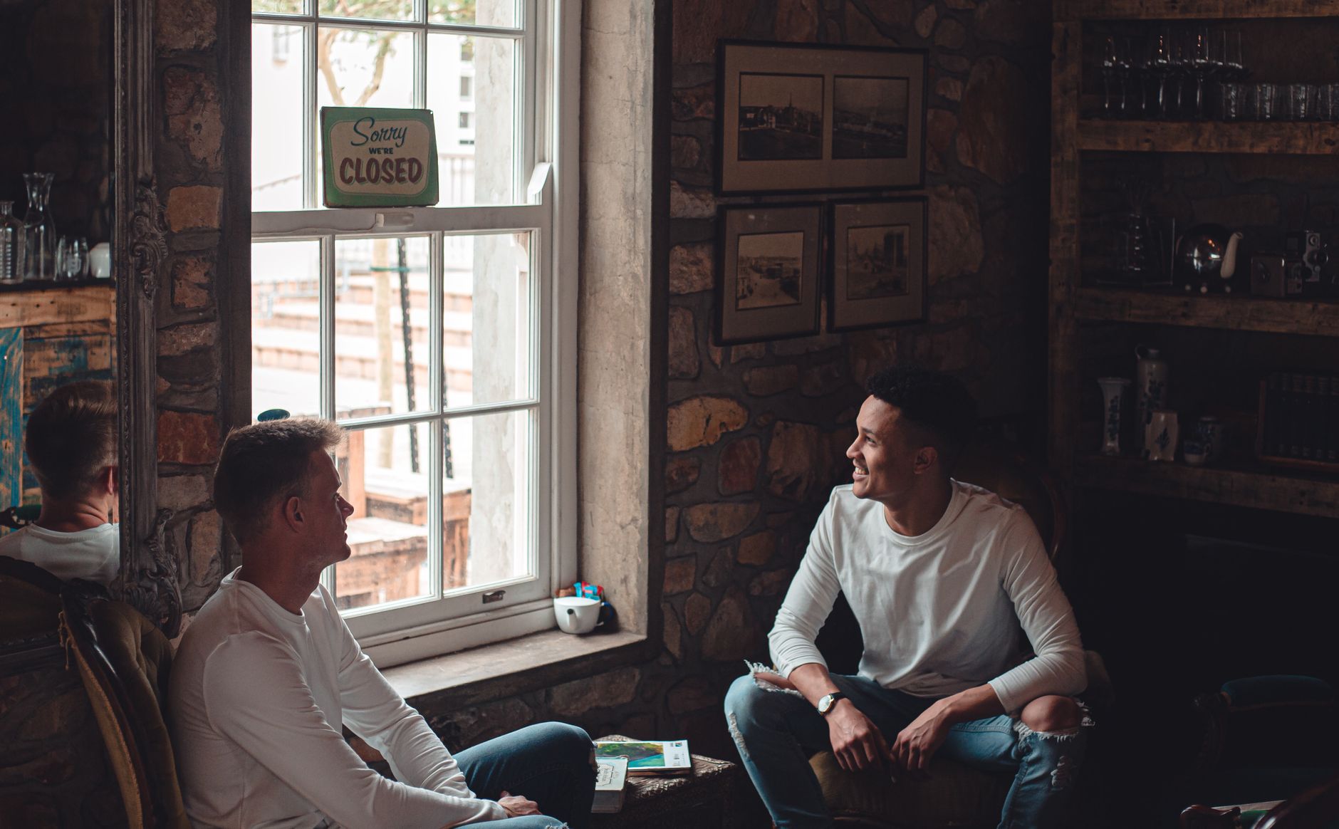 Two men talking in a room beside a window